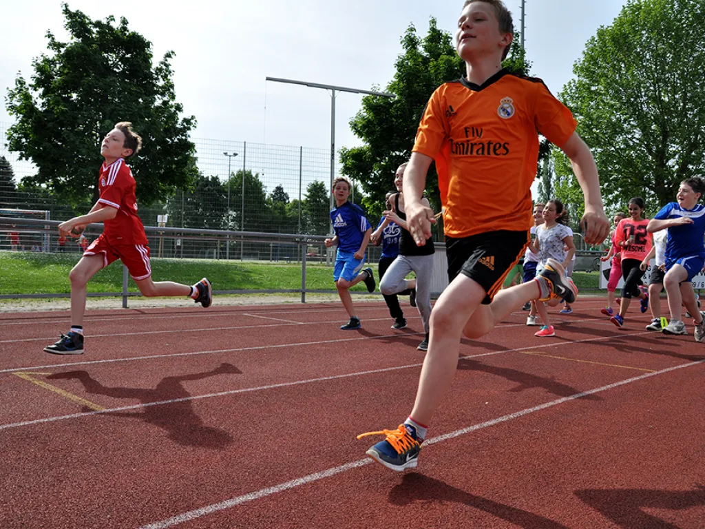 Läuferin sprintet im orangen Trikot über die Bahn.